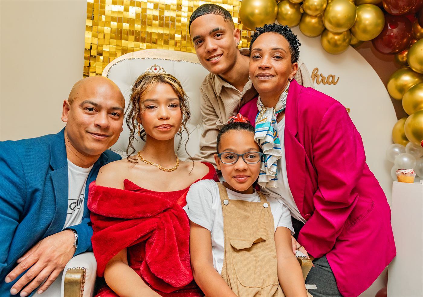 Family gathered around a young woman in a red gown before her matric farewell