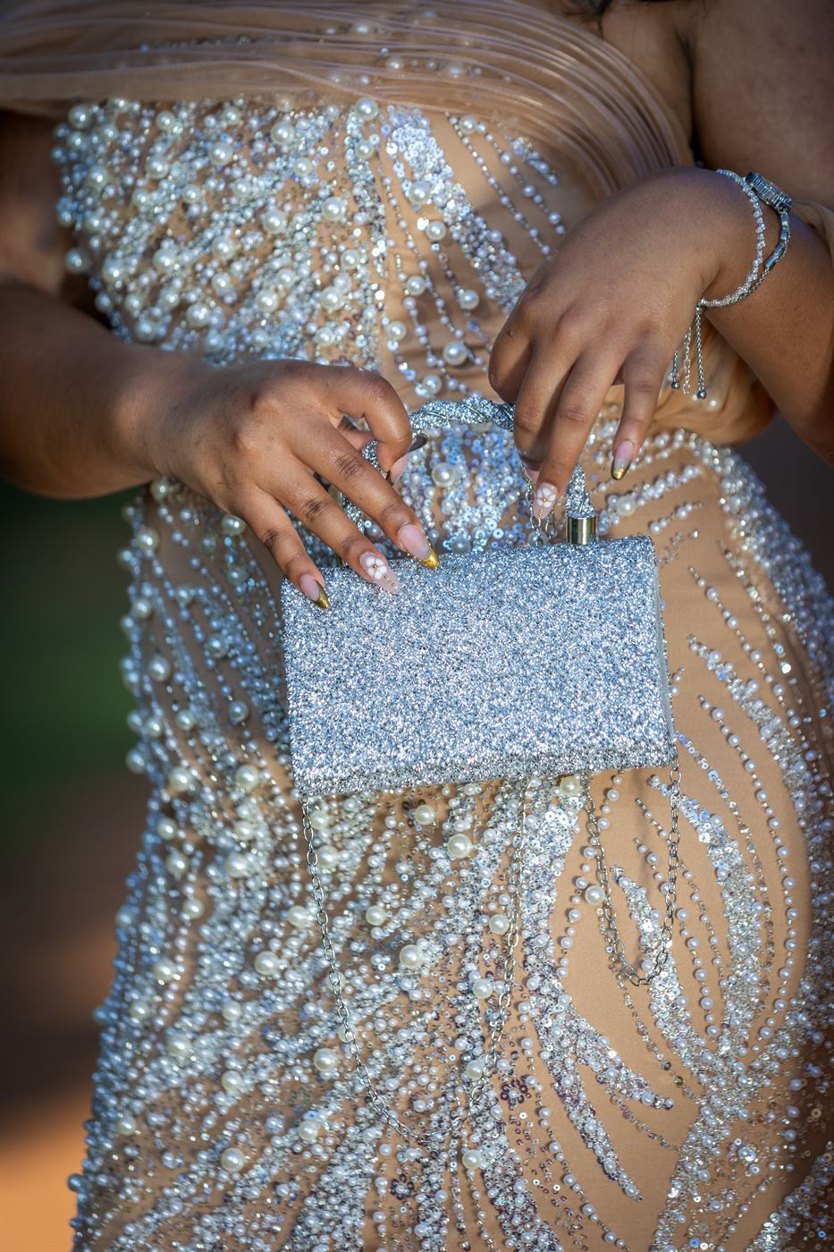 Close detail of a pearl-beaded gown and silver clutch