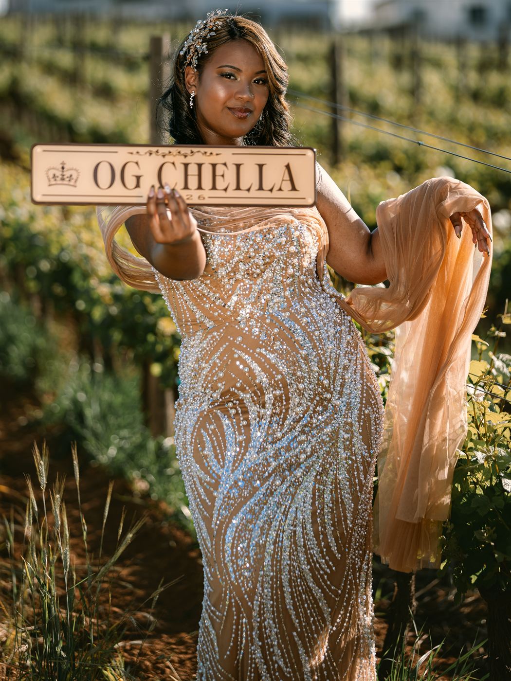 Young woman holding a carved OG Chella sign in a vineyard